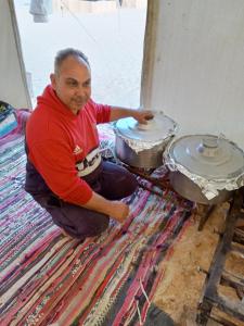 a man kneeling on the floor next to two pots at safari book in Bawati