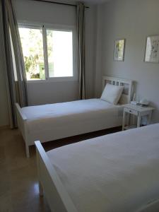 two beds in a room with a window at Elviria Beauty by the sea in Marbella +17 photos