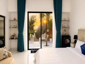 a bedroom with a bed and a window with blue curtains at Resort Hoa Loi in Vĩnh Cửu Lỏi (1)