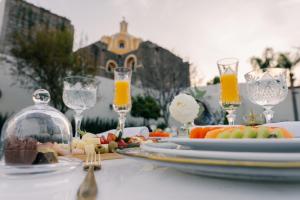 a table with a plate of food and glasses of orange juice at Hotel Casa Huamantla in Huamantla