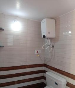 a bathroom with a toilet and a light on the wall at Swami's Yatri nivas in Akalkot