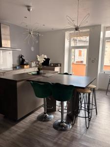 a kitchen with a table and some green chairs at Maison Spacieuse 3 chambres, billard, proche Zénith, in Pérignat-lès-Sarliève