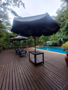 Eine Holzterrasse mit zwei Bänken und einem Sonnenschirm in der Unterkunft Hotel Jasy in Puerto Iguazú