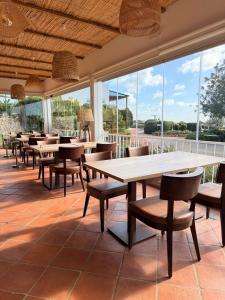 a restaurant with tables and chairs and large windows at Hotel Rural Quinta do Marco - Nature & Dining in Tavira