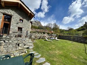 a stone building with a yard with a green bench at La Casetta in Oyace