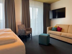 a hotel room with a bed and a couch at Casa Palatina Vinotel in Großkarlbach