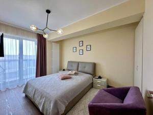 a bedroom with a bed and a purple chair at C&Y Zev Apartments in Mamaia