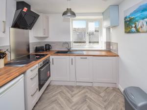 a kitchen with white cabinets and a sink and a window at Old Chapel Apartment in Kendal