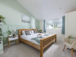 a bedroom with a large bed and a chair at Little Dunley Cottages - Willow in Bovey Tracey