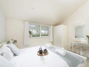 a white bedroom with a large white bed and a window at Little Dunley Cottages - Maple in Bovey Tracey