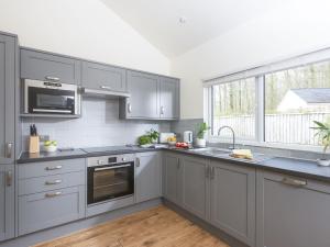 a kitchen with gray cabinets and a sink at Little Dunley Cottages - Maple in Bovey Tracey