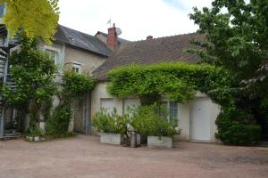 a house with two white garage doors and trees at Logis hotel Saint-Joseph in Sancoins
