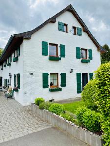 a white house with green shutters on it at Heckenstübchen in Simmerath