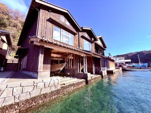 a house sitting on the water next to a river at Aoshima あおしま in Kameshima