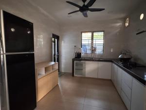 a kitchen with white cabinets and a ceiling fan at Permas Jaya Corner Homestay -Event -Party -TablePool -Karaoke -BBQ in Johor Bahru