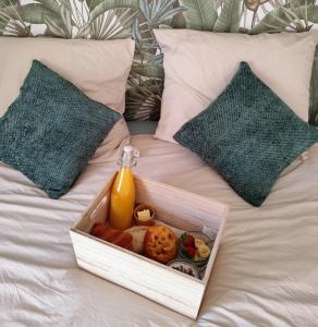 a tray of food and a bottle of orange juice on a bed at L'Orée du Bois in Pulnoy