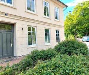 a house with a black door and some bushes at Historisches Stadthaus Schwentine in Eutin