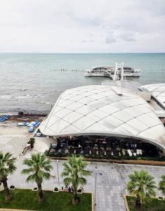 a large building next to the ocean with palm trees at Big Center Beachfront Apartment in Durrës