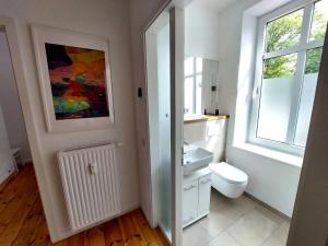 a bathroom with a sink and a toilet and a window at Historisches Stadthaus Schwentine in Eutin