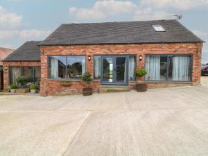 a brick house with windows and potted plants at The Croft, Home Farm in Ripley
