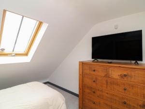 a bedroom with a tv on top of a wooden dresser at The Croft, Home Farm in Ripley