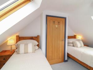 a bedroom with two beds and a wooden door at The Croft, Home Farm in Ripley