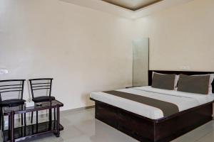 a bedroom with a large bed and two chairs at Hotel O Parinda Lodging in Chinchwad +52 photos