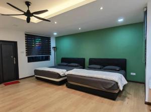 two beds in a room with a green wall at Permas Jaya Corner Homestay -Event -Party -TablePool -Karaoke -BBQ in Johor Bahru +13 photos