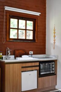 a kitchen with a sink and a microwave at Chalés Vila Do Vale in Vale do Capao +25 photos