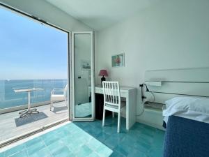 a bedroom with a bed and a desk and a balcony at La Dimora sul Mare in Sant'Angelo D'Ischia +6 photos