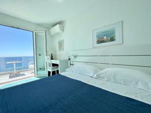 a white bedroom with a large bed and a desk at La Dimora sul Mare in Sant'Angelo D'Ischia
