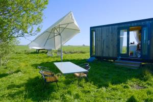 a table with chairs and an umbrella next to a tiny house at De IJsvogel in Wijdewormer