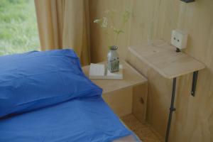 a bed with a blue pillow and a table with a vase at De IJsvogel in Wijdewormer