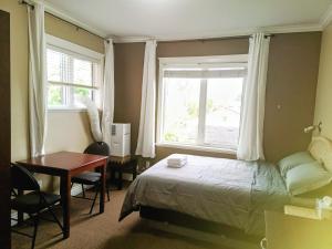 a bedroom with a bed and a desk and a window at Cold Moon Inn in Nanaimo