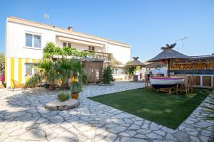 a courtyard with a house and a table and chairs at VILLA LES SALINES Maison de Vacances au Grau du Roi in Le Grau-du-Roi