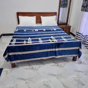 a bed with a blue and white blanket on it at Taniya Sunview - Villa in Nuwara Eliya