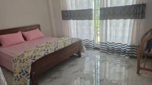 a bedroom with a bed and a window with curtains at Taniya Sunview - Villa in Nuwara Eliya