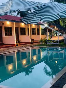 a house with a swimming pool with an umbrella at Nilaveli Shan Guest in Trincomalee