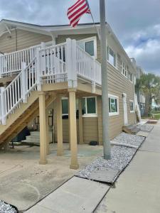 a house with a porch and an american flag at Lil' Beach Getaway in Jacksonville Beach