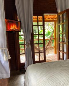 a bedroom with a bed and a window with a fireplace at Chalés Vila Do Vale in Vale do Capao