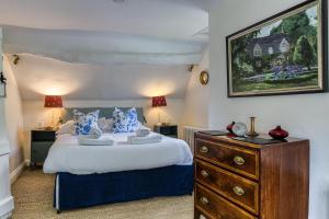 a bedroom with a large bed and a dresser at Top Cottage, Oddington in Adlestrop