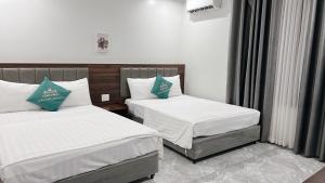 a bedroom with two beds with white and blue pillows at Tuần Châu HQT in Ha Long