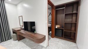 a bathroom with a television and a desk with a mirror at Tuần Châu HQT in Ha Long +7 photos