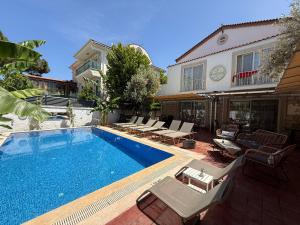 a swimming pool with chairs and a house at Rebetiko Hotel in Alaçatı