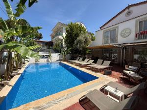 a swimming pool with chairs and a house at Rebetiko Hotel in Alaçatı