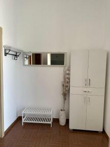 a room with a white refrigerator and a bench at Affitto nel cuore del Salento in Poggiardo