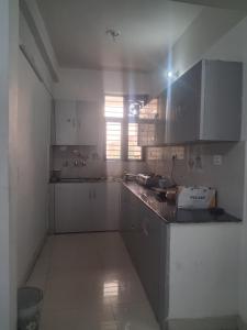 a kitchen with white cabinets and a counter top at Guruji Homestay Near UPES Collage in Jhājra +28 photos