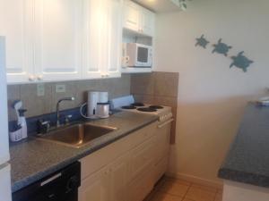 a kitchen with a sink and a stove top oven at Molokai Ocean View Condo in Maunaloa