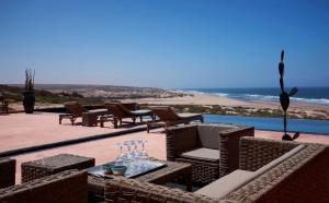 a patio with chairs and a table with wine glasses at Ksar Massa in Rbat