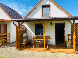 a house with a bench on a deck at DorJan - Domki Letniskowe in Dziwnówek